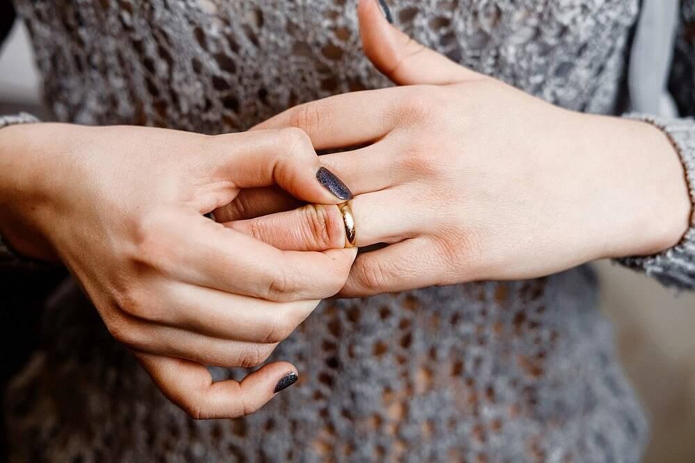 Woman taking off her wedding ring, considering divorce.