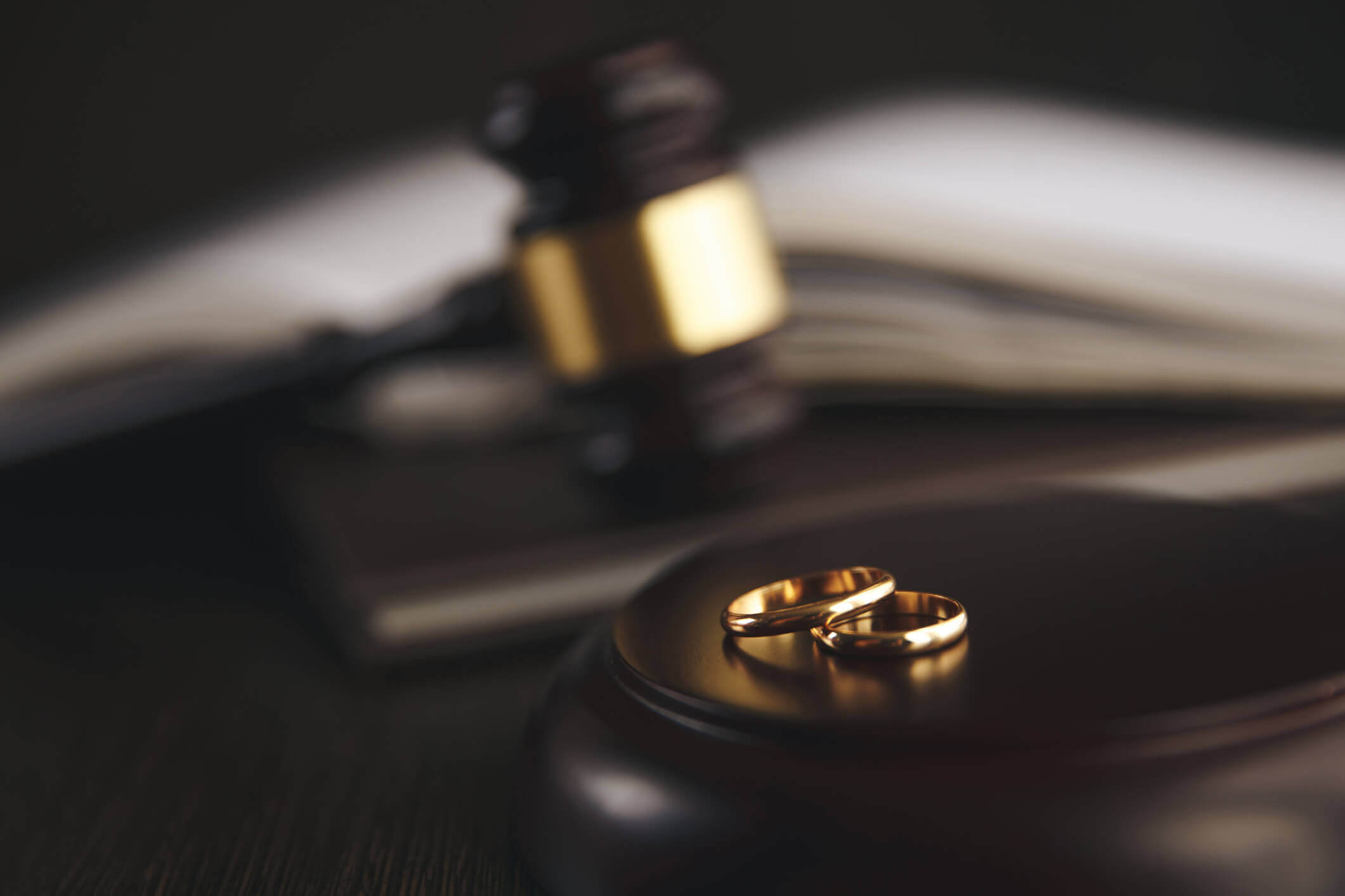 Two wedding rings separate on a desk, signifying divorce.