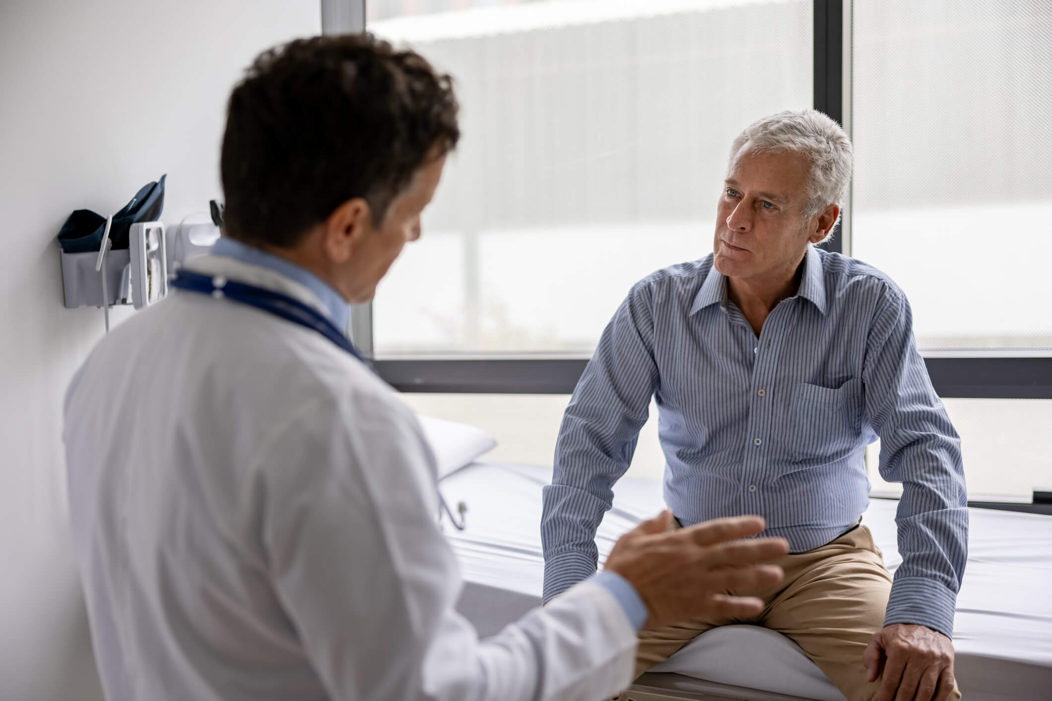 Médico latinoamericano hablando con un paciente en una consulta en su consultorio - conceptos de salud y medicina