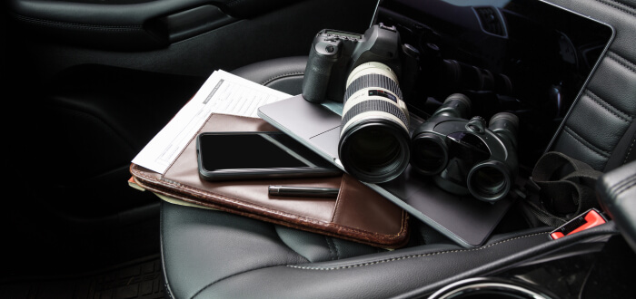Private Investigator camera, laptop, files, phone on a car seat